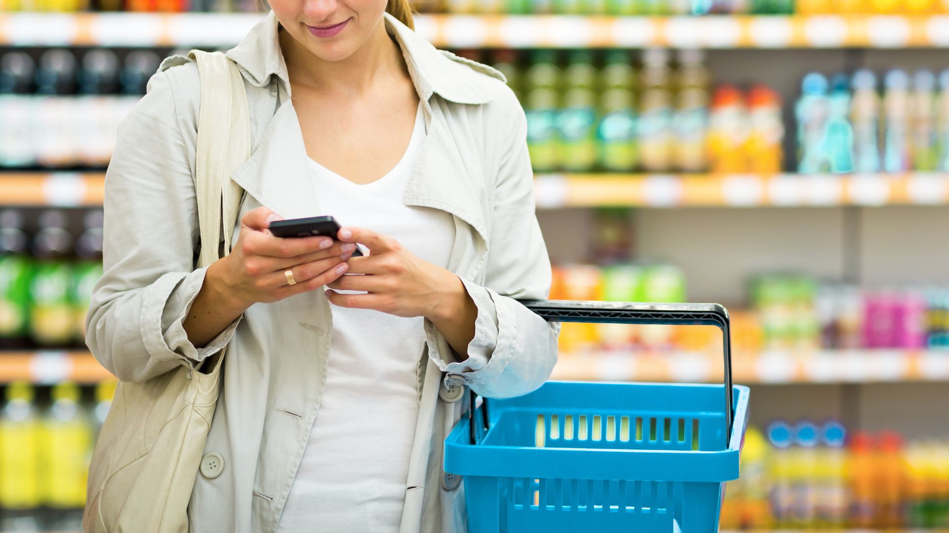 Woman shopping with cart and holding phone