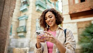 Woman outside smiling at phone