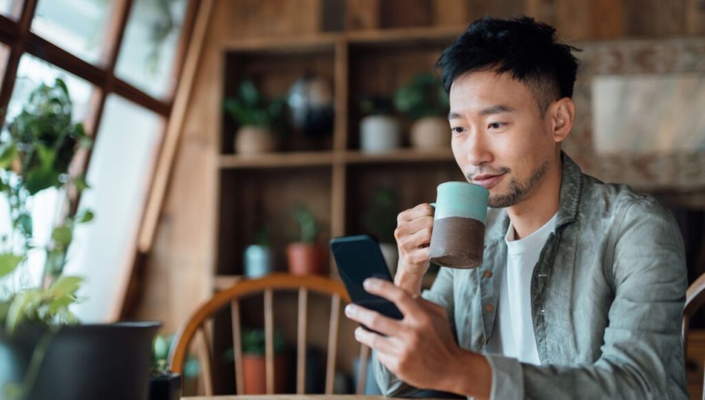 Man sipping coffee and browsing on phone