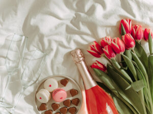 Bunch of red tulip and rose wine on bed