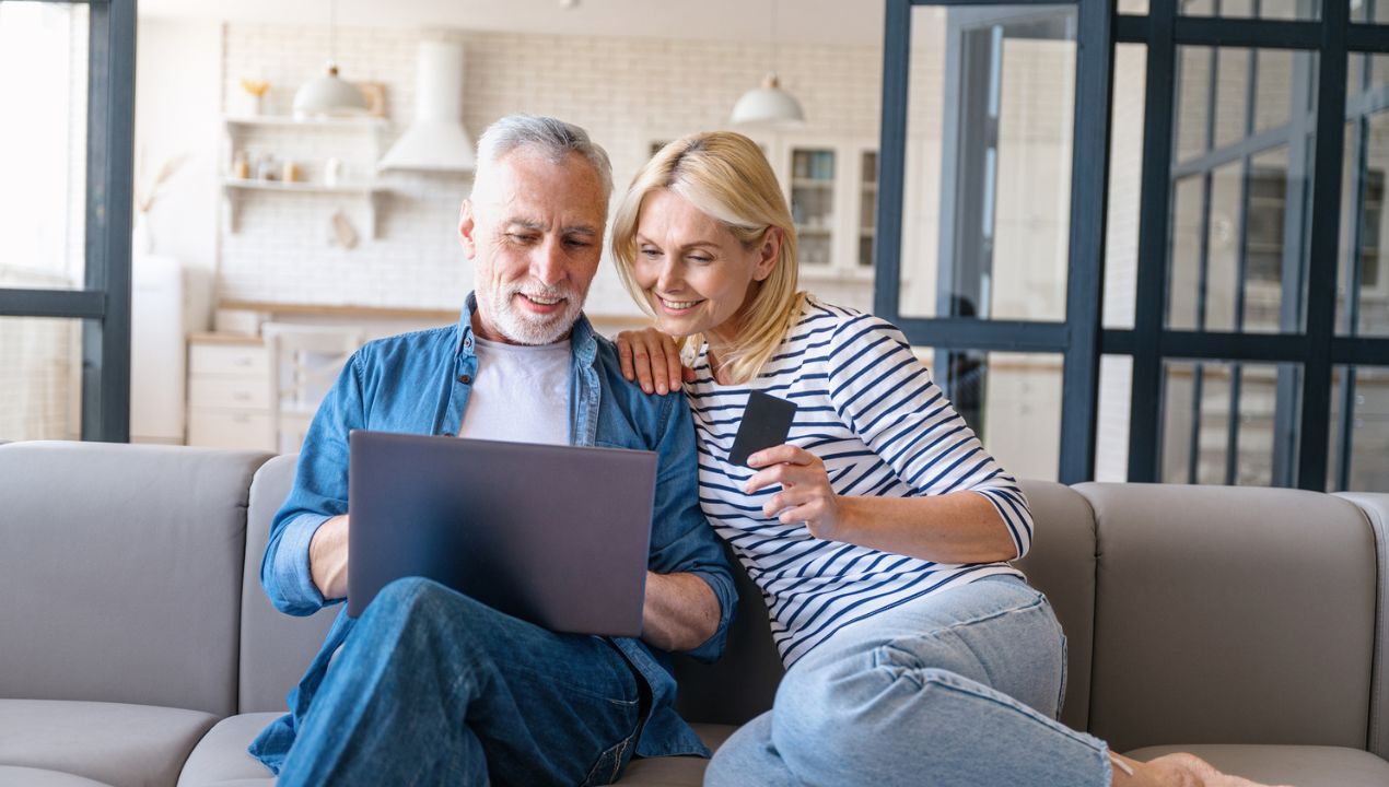 couple on couch browsing computer with credit card