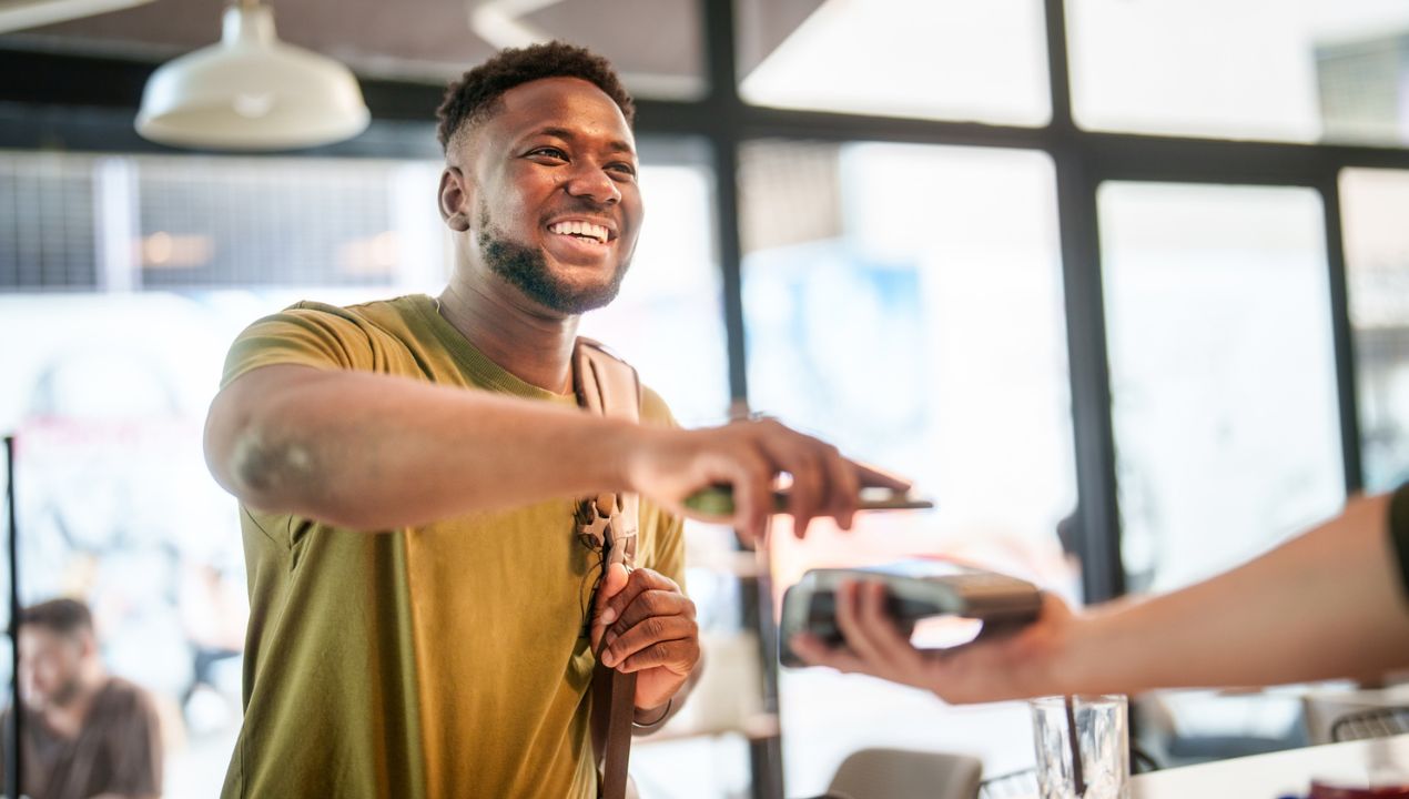Man tapping to pay at checkout and smiling